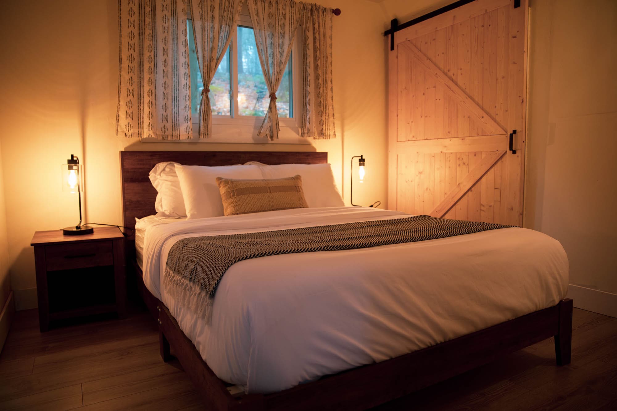 Main-floor queen bedroom with a rustic wood headboard at the Pocono A-frame cabin